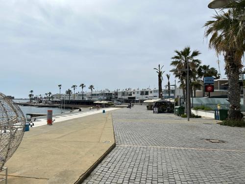 a boardwalk with palm trees and a beach with buildings at Semeli The 3As Armonia, Ariadne, Artemis in Paphos City