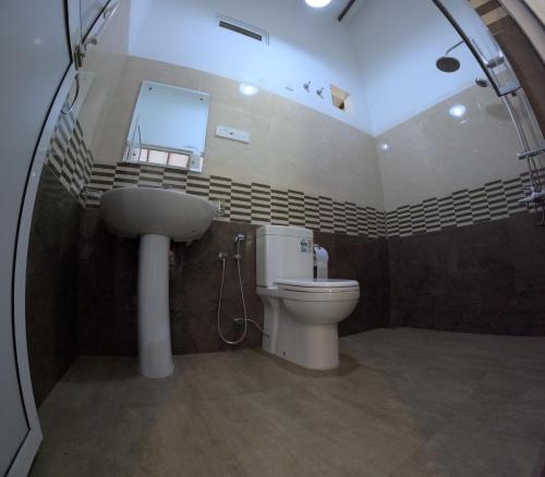 uma casa de banho com um WC, um lavatório e um espelho. em Leon Hilltop Resort em Kitulgala