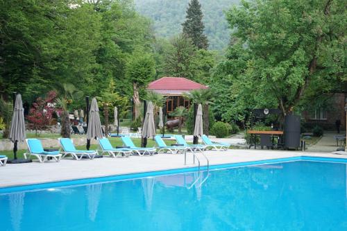 una piscina con sedie e ombrelloni di Wald Hotel Lagodekhi a Lagodekhi