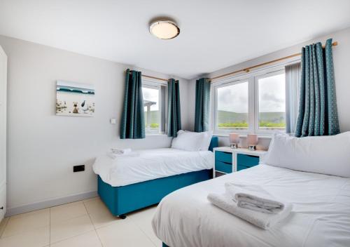 two beds in a room with two windows at Ocean Villa in Woolacombe