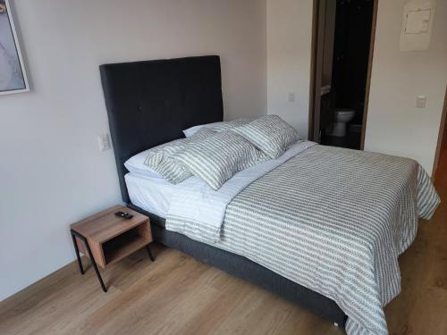 uma cama com uma cabeceira preta e uma mesa de cabeceira em madeira em Aparta Suite - Centro Internacional - Mitika em Bogotá