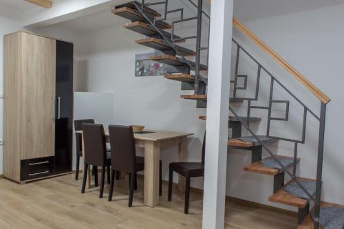 a dining room with a table and a spiral staircase at San Lux Dunavska in Novi Sad