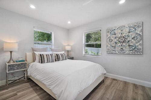 a white bedroom with a bed and two windows at Casita Delray in Delray Beach