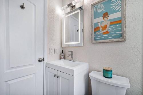 a bathroom with a toilet and a sink and a mirror at Casita Delray in Delray Beach
