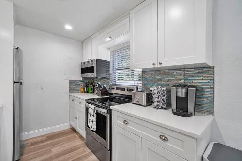 a kitchen with white cabinets and a stove top oven at Casita Delray in Delray Beach
