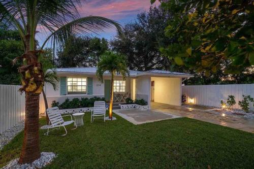 a house with a palm tree and chairs in the yard at Casita Delray in Delray Beach
