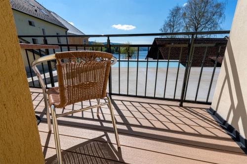 a rattan chair sitting on the balcony of a house at Pension U Kostela in Frymburk