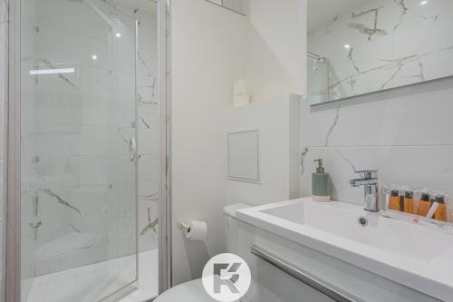 une salle de bain blanche avec une douche et un lavabo dans l'établissement R'Apparts T3 Cozy Little Nest, à Grenoble