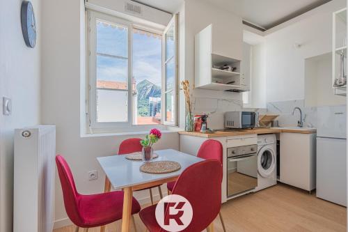 une petite cuisine avec une table et des chaises rouges dans l'établissement R'Apparts T3 Cozy Little Nest, à Grenoble