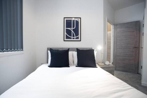 a white bed with black pillows in a bedroom at Bayard Apartments City Centre 2 Bedroom Apartment in Peterborough