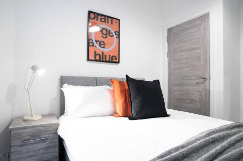 a bedroom with a large white bed with orange pillows at Bayard Apartments City Centre 2 Bedroom Apartment in Peterborough