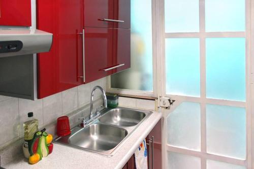 a kitchen with a sink and red cabinets at Colorida Casa Azul en Texcoco Centro WiFi Cocina in Texcoco de Mora