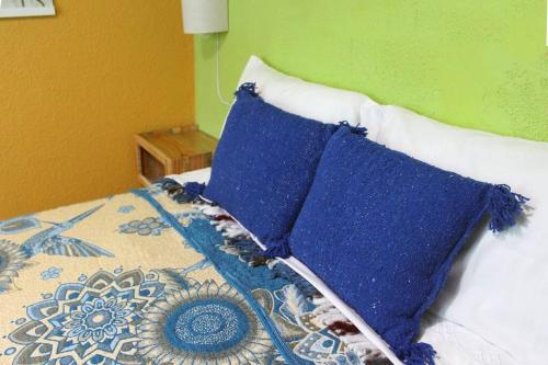 a bed with blue pillows on top of it at Colorida Casa Azul en Texcoco Centro WiFi Cocina in Texcoco de Mora
