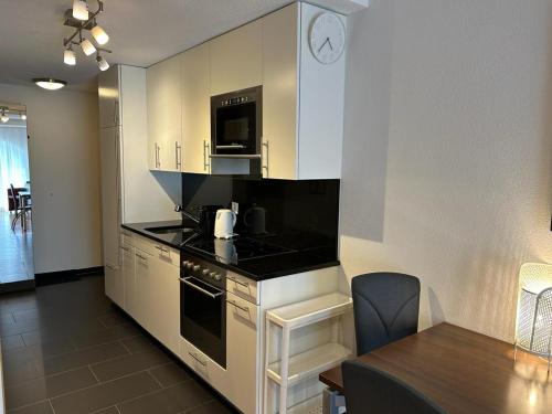a kitchen with a stove top oven next to a table at Apartments Residenz Iris in Leukerbad