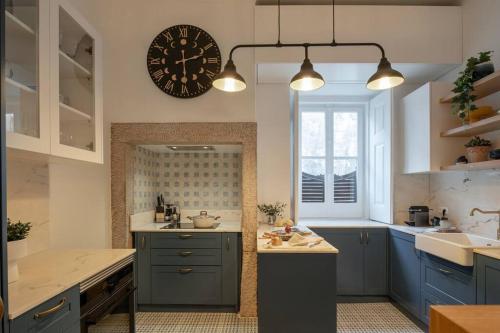 a kitchen with blue cabinets and a clock on the wall at Libest Sintra - Casa do Palácio in Sintra