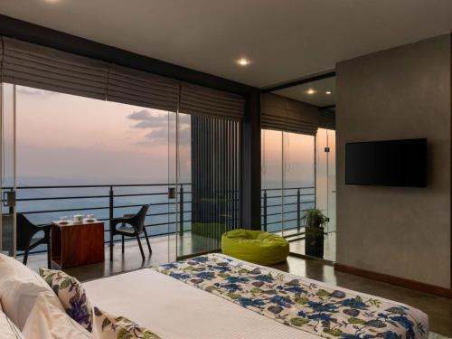 a bedroom with a bed and a balcony with a television at Green Acres Leisure Resort & Spa in Kandy