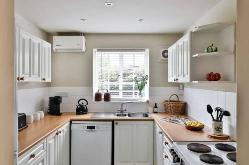 a kitchen with white cabinets and a sink at The Butlers Bungalow Beverston Castle in Tetbury