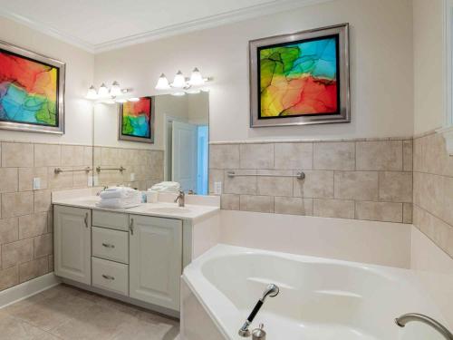 een badkamer met een bad, een wastafel en een spiegel bij Coastal Haven by Southern Vacation Rentals in Pensacola Beach