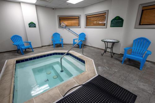 uma piscina numa sala de espera com cadeiras azuis em Wingate by Wyndham Lafayette Airport em Lafayette