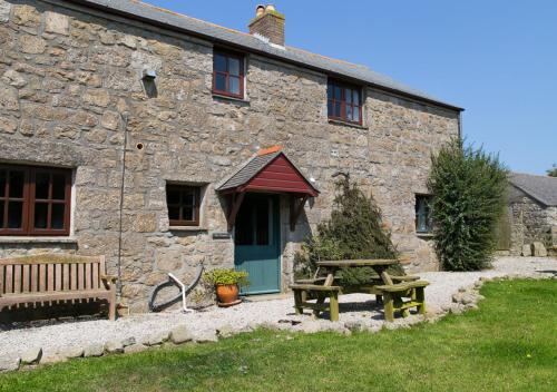 a stone house with a picnic table and a bench at The Granary in Porthcurno
