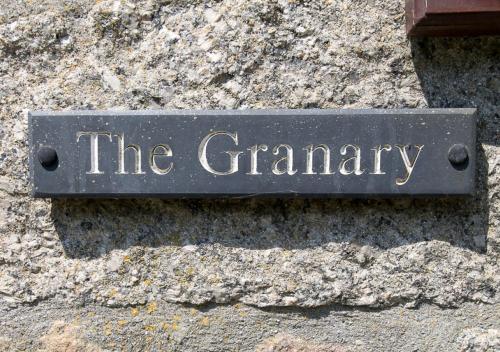 a sign that says the ceremony on a stone wall at The Granary in Porthcurno