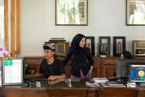 a woman standing next to a boy at a desk at Hotel Blambangan in Banyuwangi