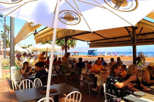 a group of people sitting at tables under umbrellas at the beach at New built 3-bed penthouse with pool, Mar de Plata in Mazarrón