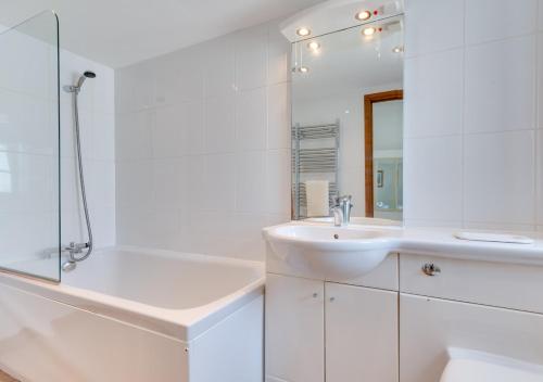 a white bathroom with a sink and a mirror at The Anchorage in Falmouth
