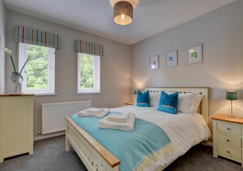 a bedroom with a large bed with blue pillows at Puffins Retreat in Braunton