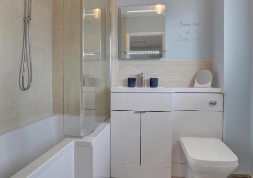 a white bathroom with a toilet and a shower at Puffins Retreat in Braunton