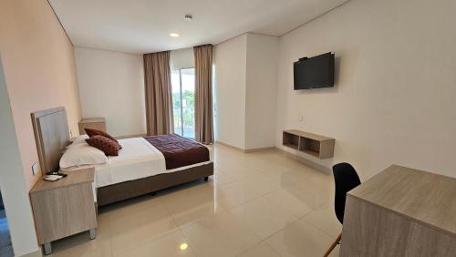 a bedroom with a bed and a tv on the wall at Hotel Santa Sofia in Puerto Salgar