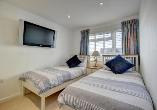 a bedroom with two beds and a flat screen tv at Pixie Croft in Braunton