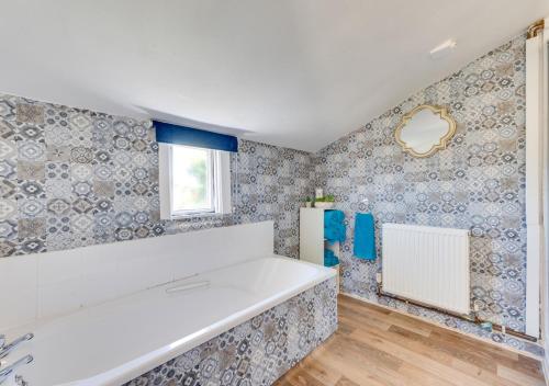 a kitchen with blue and white wallpaper and a white tub at Resthaven in Ilfracombe