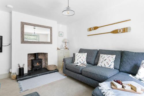 a living room with a blue couch and a fireplace at Bay Cottage, Brixham in Brixham