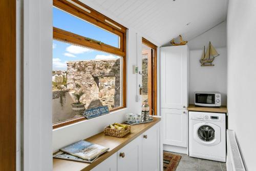 a kitchen with a window and a washing machine at Bay Cottage, Brixham in Brixham