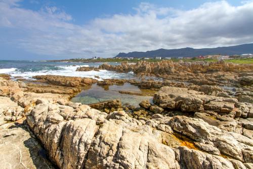 a group of rocks on the ocean with the waves at Schulphoek Seafront House in Hermanus