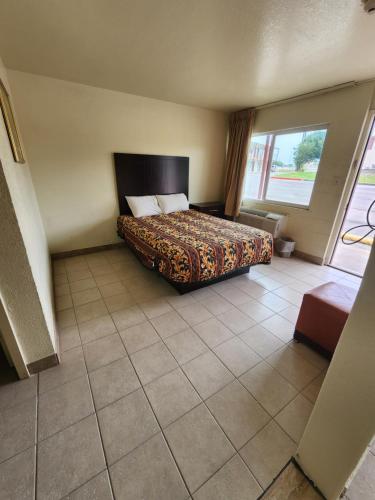 Habitación de hotel con cama y ventana grande en HomeTown Inn and Suites en Mesquite