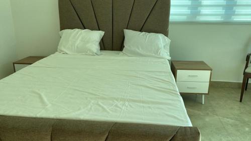 1 dormitorio con 1 cama grande con sábanas y almohadas blancas en Apartamento Juan Dolio, en Juan Dolio