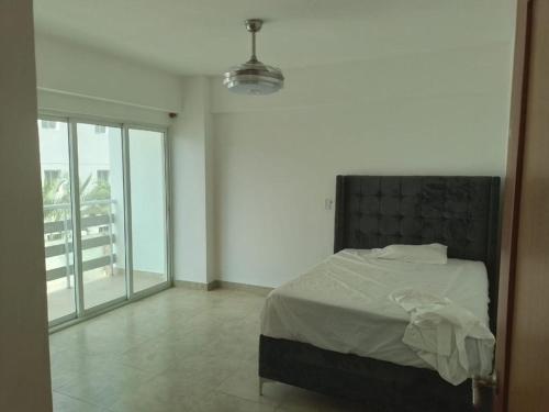 a bedroom with a bed and a large window at Apartamento Juan Dolio in Juan Dolio