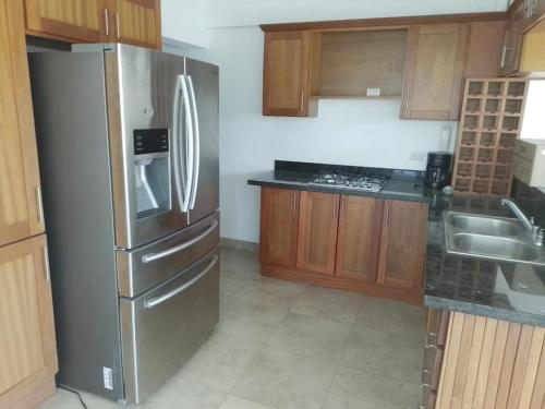 una cucina con frigorifero in acciaio inossidabile e mobili in legno di Apartamento Juan Dolio a Juan Dolio