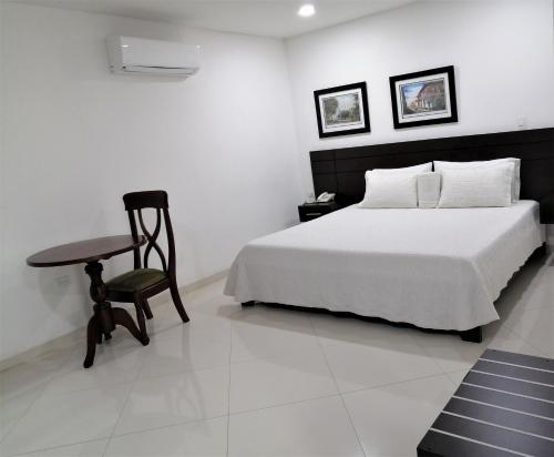 a bedroom with a bed and a table and a chair at Hotel Panorama in Sincelejo