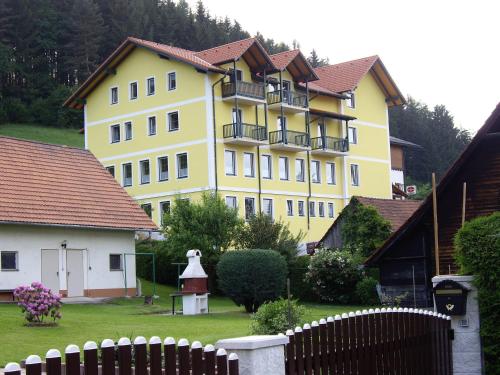 a large yellow building with a fence in a yard at Landgasthof Sepplwirt in Kindberg