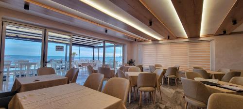 a dining room with tables and chairs and windows at Hotel Klebrido in Durrës