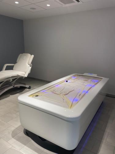 a white bed and a chair in a room at DOMITYS LES TOURMALINES in Carpentras