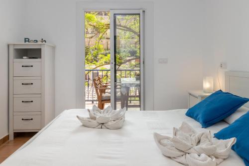 a white bedroom with two white flowers on a bed at La caseta de Sa Riera in Begur