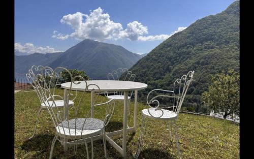 três cadeiras e uma mesa com vista para as montanhas em Gio Gio House Dizzasco Near Argegno em Dizzasco