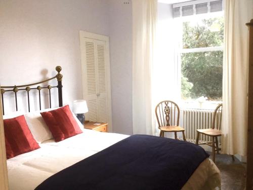 een slaapkamer met een bed met rode kussens en een raam bij Chapelhill Hideaway Isle of Bute licence AR00654F in Rothesay