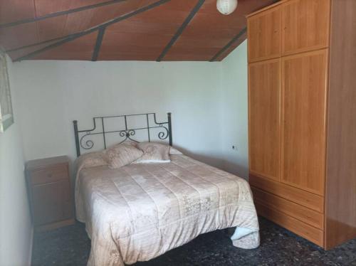 1 dormitorio con 1 cama y armario de madera en Villa Bendición - Subbética Cordobesa en Doña Mencía