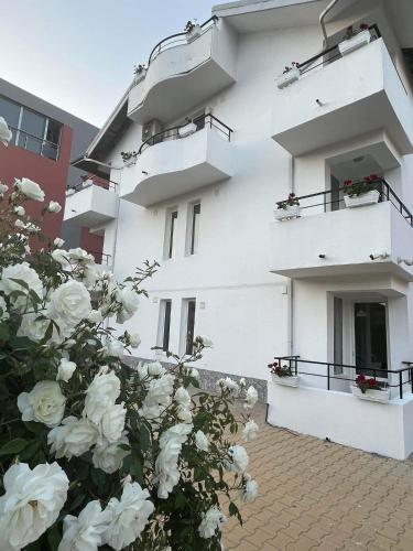 a white building with flowers in front of it at Хотел CANAVAN'S - beach in 2 minutes, free parking and WiFi in Ravda