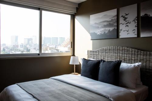 a bedroom with a large bed with a view of a city at Japandi style apartment in Polanco in Mexico City
